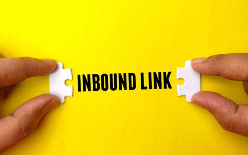 Hand holding white puzzle with text INBOUND LINK on yellow background. Business concept.